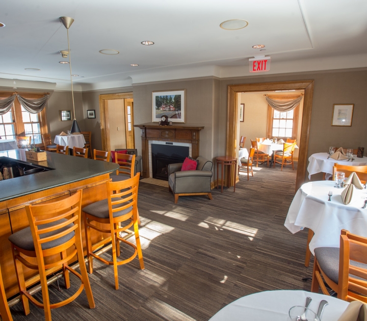 Interior photo of campus house showing the fireplace, dining area, and part of the bar