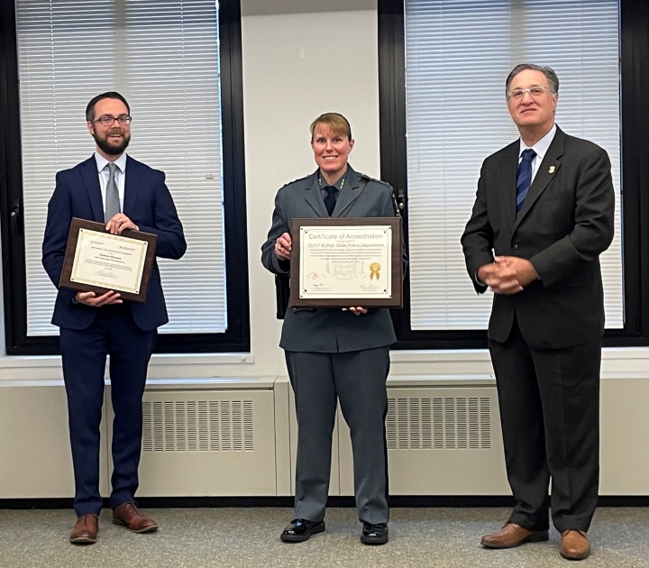 Interim UPD chief Amy Pedlow, holding framed accreditation plaque, poses with DCJS officials.