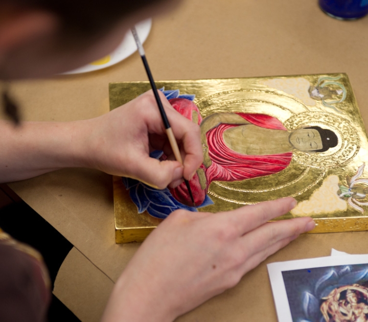 Student treating a painting with a small artist's brush