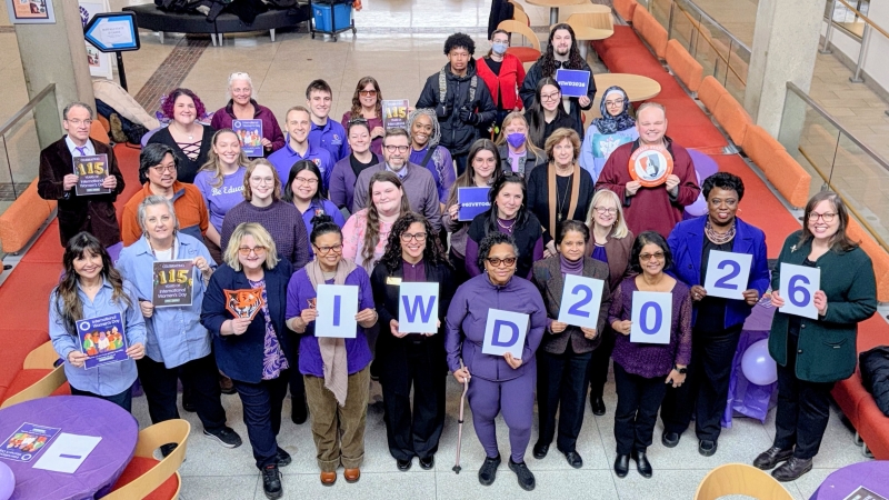 A group of faculty and staff members holding a sign that spells IWD 2026