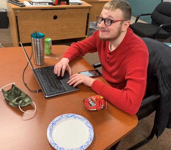 Evan O'Connell sitting at a laptop in the College Based Transition Program classroom in Bacon Hall