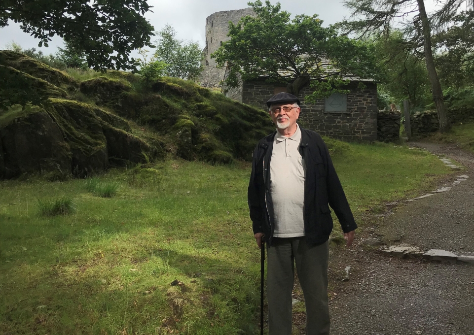 David Lampe standing on a path wearing a cap and holding a cane