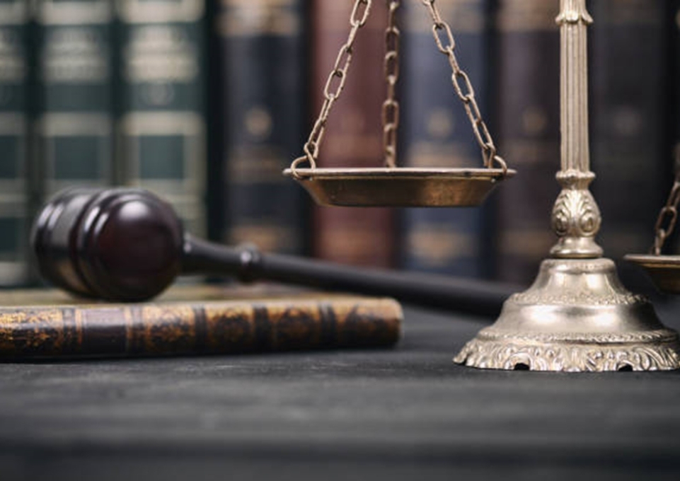 Courtroom gavel sits atop law book next to scale of justice