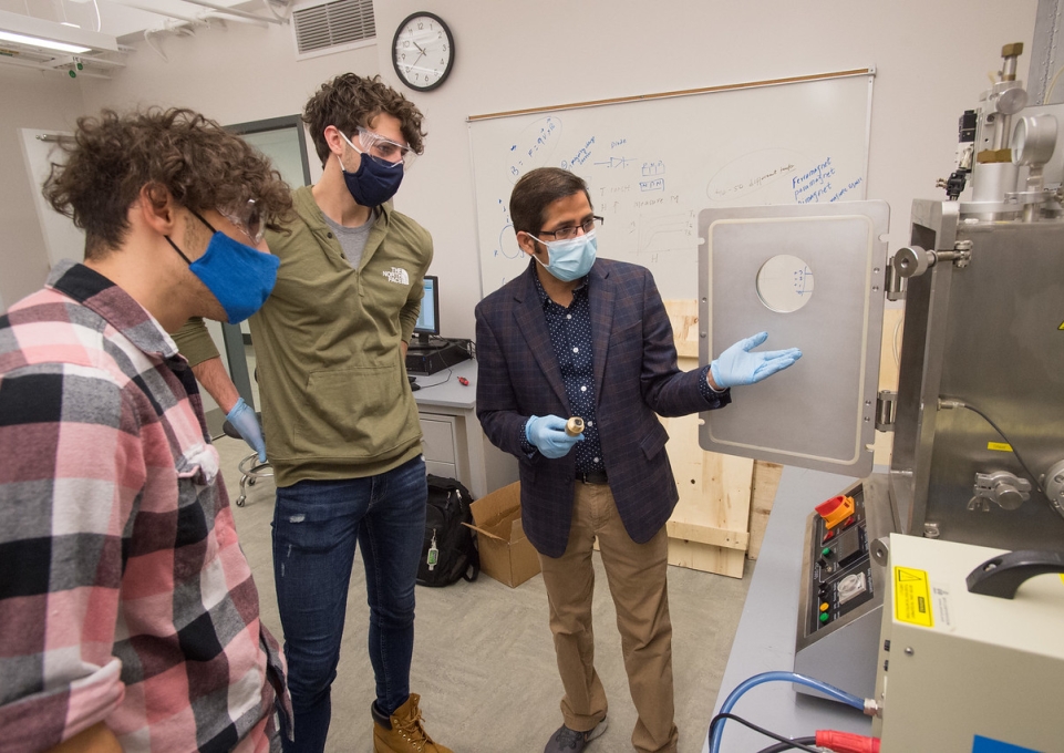 Dr. Pathak instructing two students on equipment