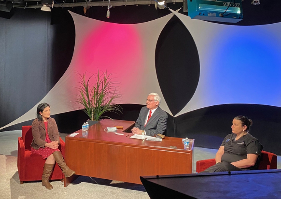 Three people on a staged set conducting an interview