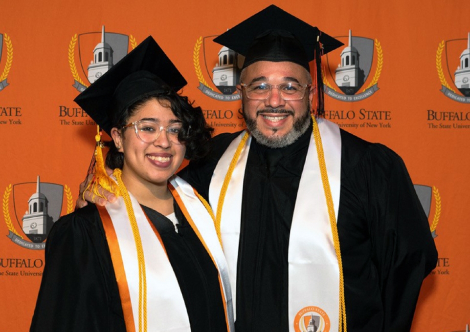 Clarimar and Cesar Galarza standing side by side smiling in caps and gowns