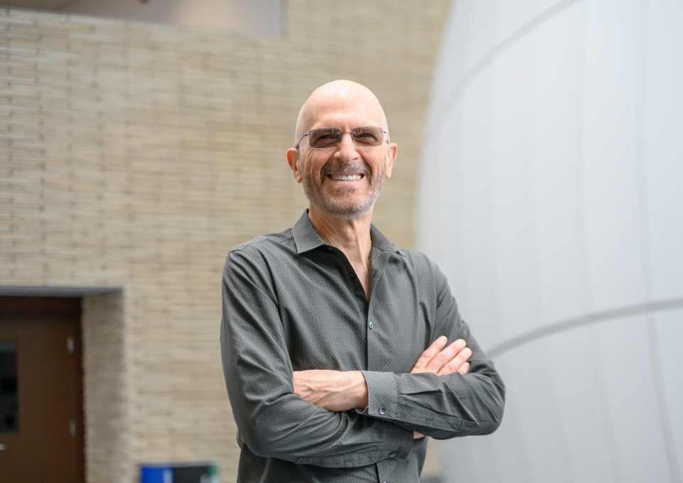 Joaquin Carbonara standing outside the Planetarium, smiling with arms crossed