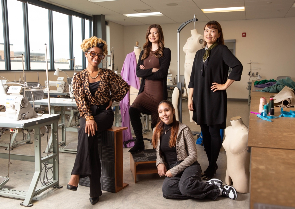 Fashion textile technology students and their faculty adviser pose with sewing machines and dress forms in the fashion laboratory