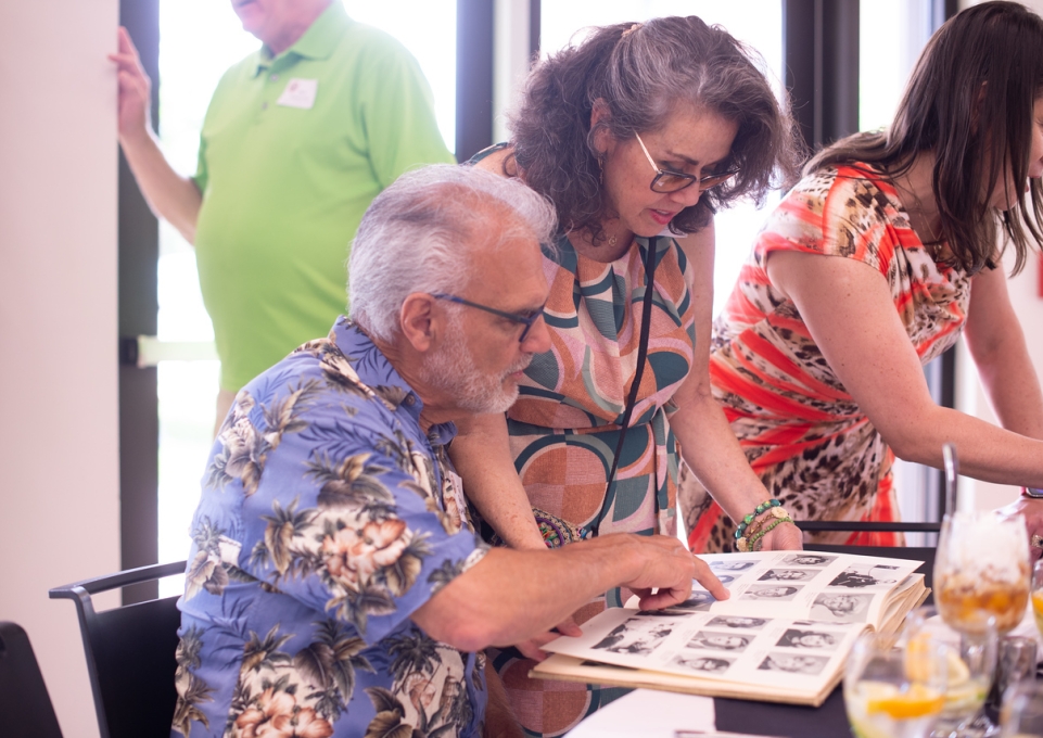 Two alumni pore over an old Elm yearbook at the 50-Plus Alumni Reunion Luncheon