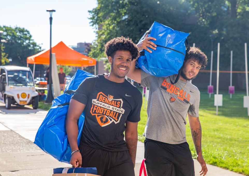 Two students carrying luggage on move-in day